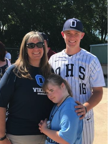 A family of three smiling at son's baseball game