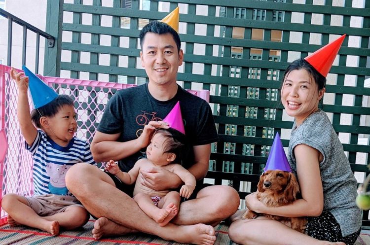 Family of four and a dog sitting on their deck wearing party hats