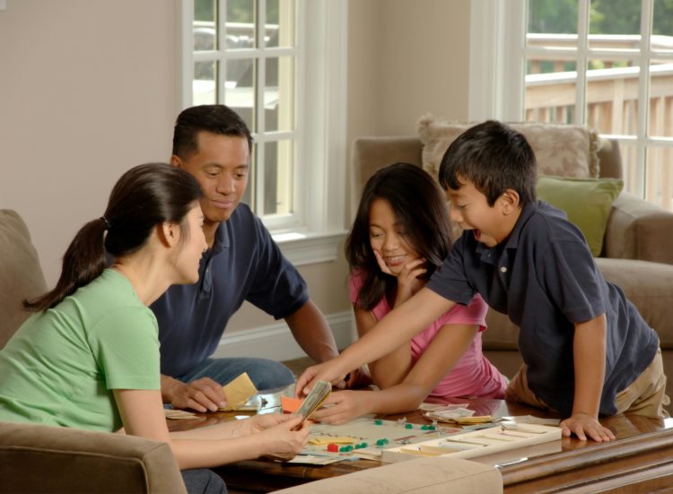 A family of four playing a board game at home.